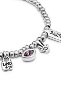 Pulsera de plata con cuentas redondeadas, que presenta una piedra morada, un colgante con un símbolo de mano y dos etiquetas inscritas con "UNO de 50" y "SUERTE".