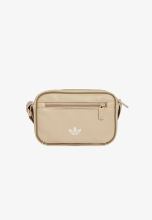 Pieni beige crossbody-laukku, jossa edessä vetoketjutasku ja valkoinen Adidas-logo yksivärisellä valkoisella taustalla.