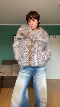 Valse bontjas in grijs met luipaardpatronen, met een pluizige textuur en een ontspannen pasvorm. Gecombineerd met lichtgewassen jeans met wijd uitlopende pijpen.