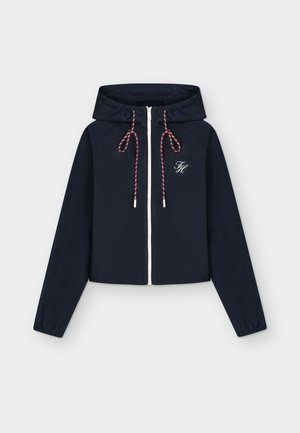 Marineblaue Kapuzenjacke mit Reißverschluss, elastischen Bündchen, weißen und roten Kordeln und weiß besticktem "FH"-Logo auf der linken Brust.