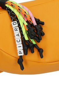 Sac synthétique orange avec une surface texturée. Six cordons colorés tressés avec des accents noirs et des perles blanches en forme de lettres épelant "PICARD."
