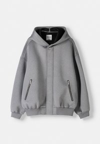 Grijze capuchontrui met rits aan de voorkant, twee zwarte zijzakken met rits, geribbelde boorden en een zachte fleece textuur.