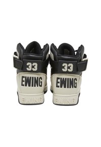Visoke tenisice u crnoj i krem koži, s podesivim remenom, velikim "33" na peti i "EWING" brendiranjem sa strane.