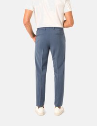 Hellblaue Anzughose mit schlanker Passform, aus strukturiertem Stoff, mit zwei Gesäßtaschen und kombiniert mit weißen Sneakern.