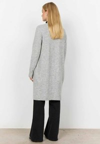 Lange grijze gebreide cardigan met geribbelde zoom, fitted mouwen en een effen textuur, gecombineerd met zwarte wijde broekspijpen.