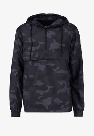 Czarna kurtka typu windbreaker w kamuflażu z kapturem, z przodem na ćwierć zamka błyskawicznego i elastycznymi mankietami. Gładki, lekki materiał o matowym wykończeniu.