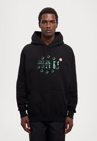 Black hoodie made of cotton with a front kangaroo pocket. Features green text and star patterns. Includes a small red logo accent.