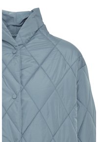 Veste matelassée bleu clair avec couture en losange, fermeture à boutons-pression et col montant.