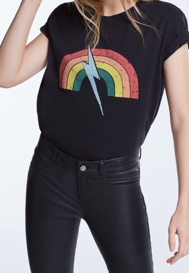 Sort t-shirt med forvasket regnbue-grafik og lynmotiv. Kombineret med tætsiddende sorte bukser. Korte ærmer og afslappet pasform.