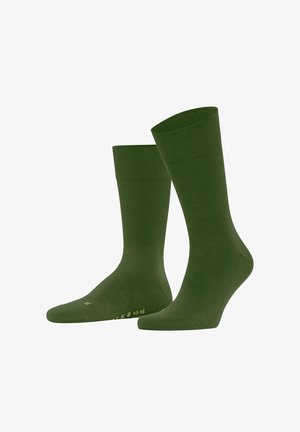 Paar schlichter, dunkelgrüner Socken in Knöchellänge, dargestellt stehend, wobei eine Socke leicht nach vorne geneigt ist.