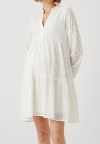 Weißes Kleid aus strukturiertem Baumwollmaterial mit Lochmuster, ausgestattet mit V-Ausschnitt, langen Ärmeln und einem gestuften Rock.