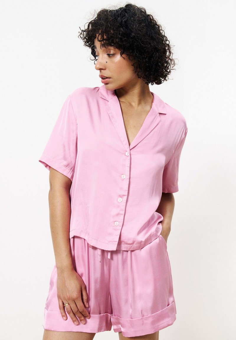 Rosa satinierter Kurzarm-Pyjama-Set mit Knopfleiste-Oberteil und Shorts mit elastischem Bund, die einen lockeren Schnitt und eine glatte Textur aufweisen.