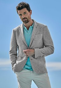 Gray, textured blazer over a light blue polo shirt; light pants. Casual, tailored fit with subtle detailing and a modern, clean design.