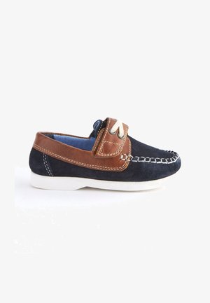 Granatowe i brązowe zamszowe buty typu boat shoes z białą gumową podeszwą, dekoracyjnym przeszyciem oraz zapięciem typu slip-on, ozdobione skórzanym paskiem i akcentem sznurowania.
