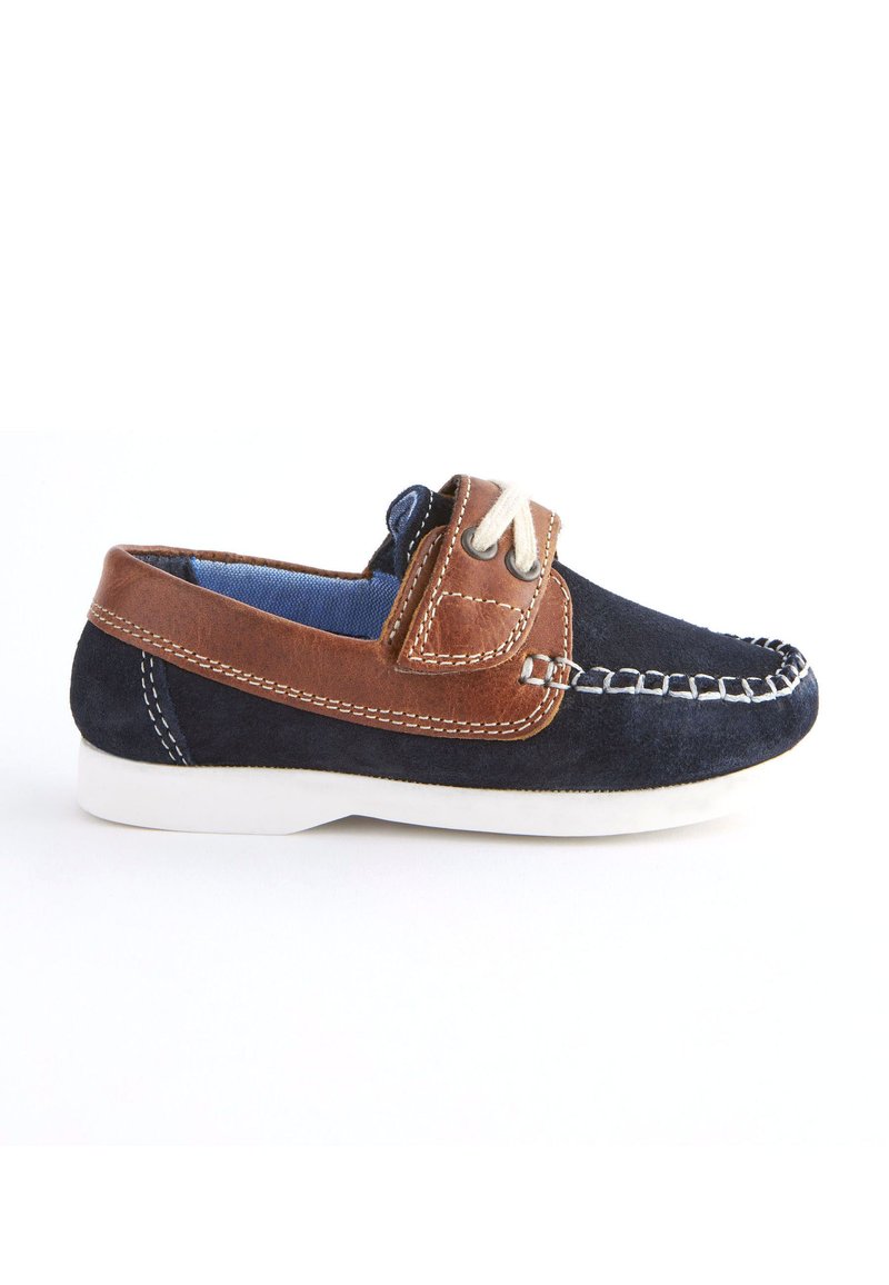 Marineblauer und brauner Wildleder-Bootsschuh mit weißer Gummisohle, dekorativer Naht und Schlupfdesign, das mit einem Lederband und einer Schnürsenkel-Akzent versehen ist.