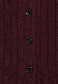 Cardigã de malha canelada em cor burgundy com cinco botões pretos, apresentando um tecido texturizado e linhas verticais para um detalhe adicional.