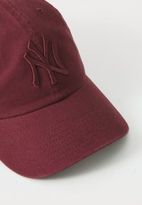 Bordo bejzbolski šešir s zakrivljenim vizorom, s vezenim logotipom "NY" u usklađenoj boji i teksturiranim pamučnim materijalom.