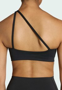 Bra sportivo nero a coste con spalline sottili e regolabili e una fascia ampia. Presenta un design semplice e minimalista, adatto all'abbigliamento attivo.