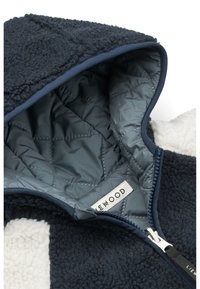 Giacca a vento in fleece navy con fodera trapuntata azzurro chiaro, zip argentata e un'etichetta con la scritta "Lifewood". Tessuto testurizzato e accogliente.