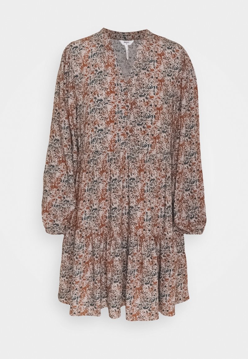 Robe florale avec des manches longues, un décolleté en V et un bas à volants. Présente un mélange de couleurs terreuses comme le brun, la rouille et le vert dans un tissu léger.