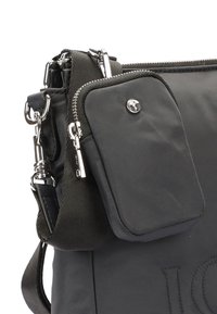 Svart tygaxelremsväska med framficka med dragkedja, avtagbar rem och detaljer i silvermetall.