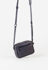 Borsa a tracolla rettangolare in pelle viola scuro, con tasca frontale con zip e tracolla regolabile. Texture liscia con hardware a contrasto.