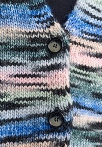 Gebreide cardigan van veelkleurig garen met horizontale strepen in blauw, groen, roze en zwart. Twee zwarte knopen zorgen voor de sluiting.