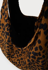 Prindi leopardmustriga kott pruunis ja mustas tekstuurses kangas, millel on avar must sisu ja lukuga tasku.