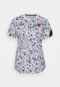 Jersey blanco de manga corta con un patrón abstracto en azul marino, que presenta un escote redondo y un emblema de gallo bordado en rojo en el pecho.