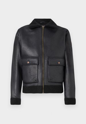 Veste en cuir noir avec fermeture éclair à l'avant, deux poches à rabat et un col et des poignets en laine, avec une finition texturée et un design structuré.