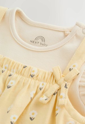 Žluté květinové šaty s žebrovaným krémovým živůtkem, vybavené elastickým pasem a mašlí na ramínku; měkký bavlněný materiál.