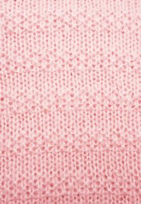 Πλεκτό ύφασμα σε απαλό ροζ, με υφή που αποτελείται από ομοιόμορφα κατανεμημένα ράμματα, προσφέροντας μια ζεστή και άνετη εμφάνιση.