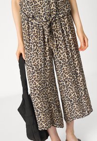 Leopardprint culottes van lichtgewicht stof, met een strik taille en geplooid ontwerp. Gecombineerd met een gestructureerde zwarte tas.