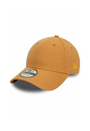 Adjustable baseball cap in sandy tan, featuring a rounded crown, a curved visor, and a circular branded patch on the front. Yellow stitching detail.