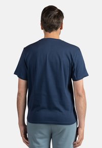 Mørkeblå bomulds t-shirt med korte ærmer, rund hals og en glat tekstur, set bagfra. Ingen synlige mønstre eller detaljer.