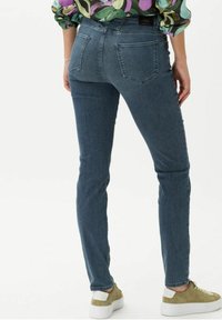 Smal passform blå denimjeans med två bakfickor, lätt blekning på låren och medelhög midja. Matchade med ljusa sneakers.