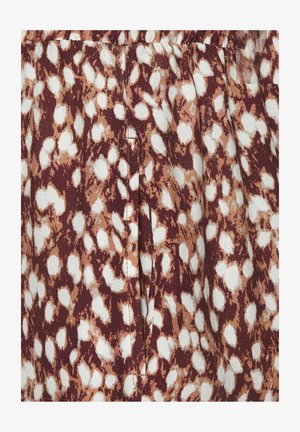 Braun-weißes tierisches Musterstoff mit Falten und sichtbaren vertikalen Nahtnähten.