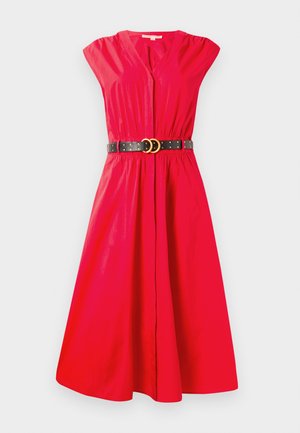 Punane puuvillane kleit lühikeste varrukatega, V-kaelusega, vöökoht on rõhutatult, must vöö, millel on kuldsed topeltringid ja studid. Laienev seelik, mille pikkus ulatub põlvedeni.