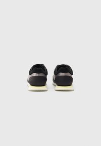 Sorte sneakers med en glatt overdel, semskede detaljer og en hvit såle. Har en rund form og et minimalistisk design.