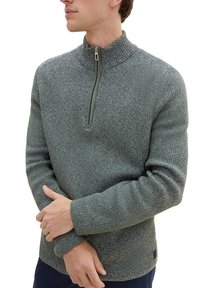 Grüner Strickpullover mit hohem Kragen und halbem Reißverschluss. Mit einem strukturierten Muster und gerippten Bündchen sowie dezenten mehrfarbigen Flocken.