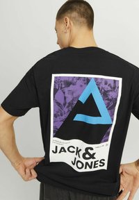 T-shirt nera in cotone con una grafica sul retro, con sfondo viola, triangolo blu e testo: "JACK & JONES."