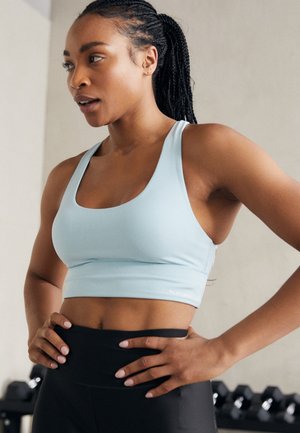 Soutien-gorge de sport bleu clair avec un décolleté large en scoop et un design ajusté. Présente un accent logo sur l'ourlet inférieur. Tissu texturé.