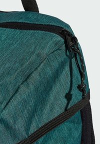 Teal fabric backpack featuring a textured finish, black zipper, and webbing accents. Secure drawstring detail at the top.