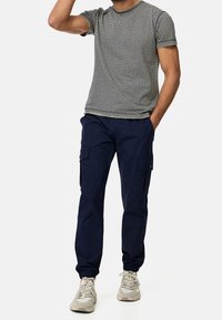 Grå kortärmad stickad t-shirt med ett texturerat mönster, i kombination med marinblå cargobyxor med sidofickor och elastiska muddar.