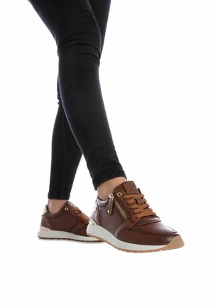Zapatillas de cuero marrón con cordones beige, detalle de cremallera y suela blanca. Presenta un acabado texturizado y acentos dorados en los laterales.