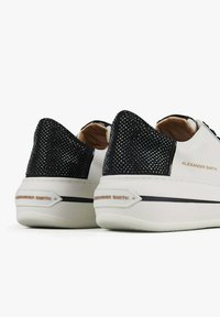 Weiße Sneaker mit einer schwarzen Mesh-Ferse, ausgestattet mit einem schlanken Design, strukturiertem Obermaterial und "Alexander Smith" Branding an der Seite.