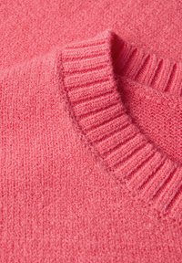 Sweater rose tricoté avec un col côtelé et une texture douce, ayant une apparence légèrement duveteuse et une couleur uniforme.