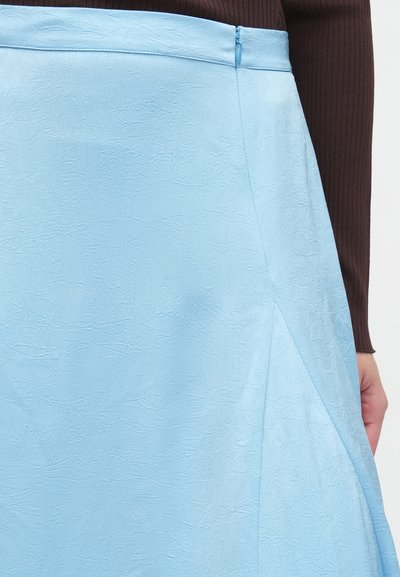 Φούστα σε γραμμή Α σε ανοιχτό μπλε, κατασκευασμένη από τσαλακωμένο ύφασμα. Διαθέτει πλευρικό φερμουάρ και καθαρές ραφές, με λεία υφή και ελαφρώς γυαλιστερό φινίρισμα.