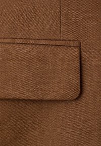 Rjava tkanina z teksturo in pravokotnim žepom s poklopcem, ki ima horizontalni šiv in natančno obrobno šivanje.