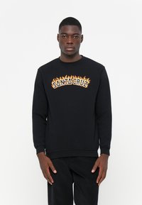 Zwarte sweatshirt met ronde hals, versierd met een vlammenpatroon in oranje en geel met de tekst "SANTA CRUZ" op de borst.